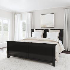 a bed with white pillows and black headboard