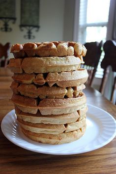 a stack of food sitting on top of a white plate next to a wooden table