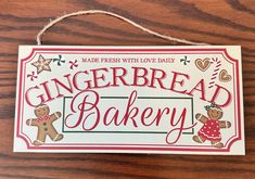 a gingerbread bakery sign hanging on a wooden table with hearts and stars around it