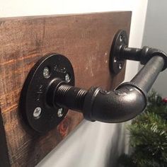 an industrial pipe is mounted to the side of a wooden wall next to a christmas tree