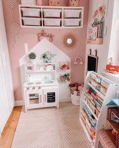 a child's playroom with pink walls and white furniture, including a doll house