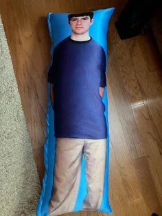 a young boy laying on top of a blue pillow with a man's face on it