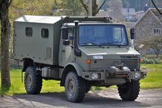 an army truck is parked on the side of the road in front of some trees