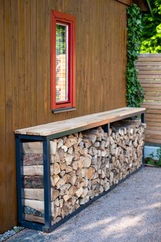 a bench made out of logs in front of a wooden building with a red window