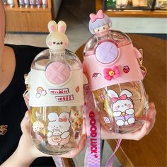 a woman holding two hello kitty water bottles