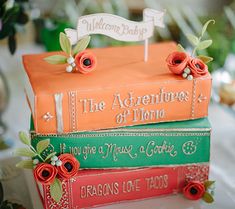 three books stacked on top of each other in front of a table with flowers and greenery