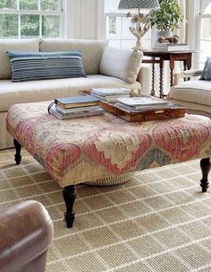 a living room filled with furniture and a coffee table on top of a rug in front of a window