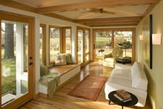 a living room filled with furniture and lots of windows covered in wood planks on the walls