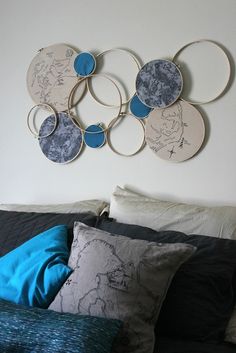 a bed topped with lots of pillows next to a wall mounted art piece