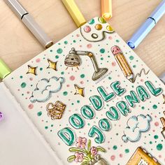 a notebook with doodle journal written on it next to some pens and pencils