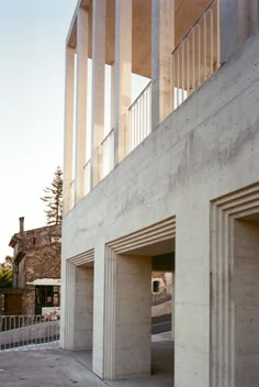 an empty parking lot next to two tall concrete buildings with columns on the top and bottom