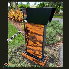 an outdoor fountain made out of wooden planks and black metal accents, sits in the grass