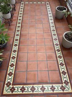 a tiled walkway with potted plants on the side and another planter next to it