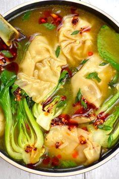 a pot filled with dumplings and broccoli covered in sauce