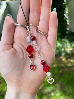 a hand is holding some red and white beads