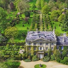 an aerial view of a large house in the middle of a lush green park area