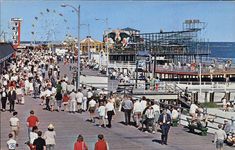 many people are walking on the boardwalk by the water