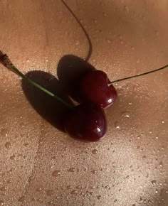 two cherries sitting on top of a wet surface