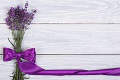 a purple ribbon and some flowers on a white wooden surface