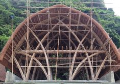 a large wooden structure sitting on top of a lush green hillside