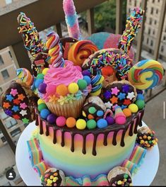 a multicolored cake with lots of candies and lollipops on top