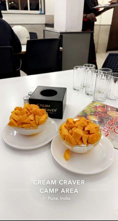 two white plates topped with food on top of a table next to glasses and a book