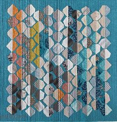 a quilted wall hanging on the side of a blue wall with many different colors