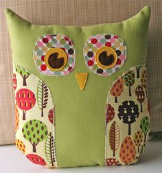 a green pillow with an owl design on it's face and eyes, sitting on a couch