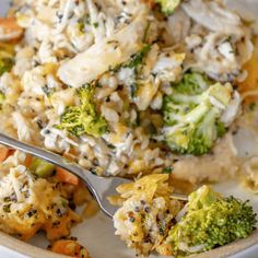 a white plate topped with broccoli and rice covered in sauce next to a fork