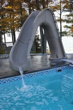 an inflatable water slide sitting next to a swimming pool with trees in the background