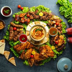 a platter filled with meats and sauces on top of lettuce