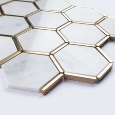 white and gold hexagon tiles with golden edges on a white table top, viewed from above