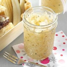 a jar filled with food sitting on top of a table next to a knife and fork