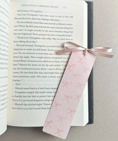 an open book with a pink ribbon tied to it