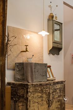 an old wooden cabinet with two towels on top and a clock in the back ground