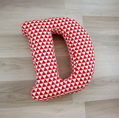 the letter d is made out of red and white fabric with triangles on it's sides