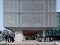 several people are standing in front of a building that has glass walls on the sides