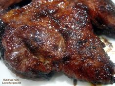 some meat is sitting on a white plate with brown stuff all over it's surface