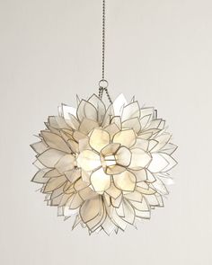 a large white flower shaped light hanging from a chain on a wall in a room