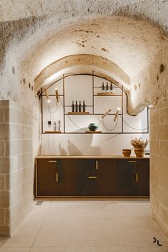 an arched room with shelves and cupboards on the wall, along with a potted plant