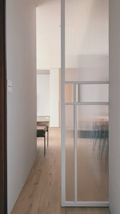 an open door leading into a room with white walls and wood flooring on the side