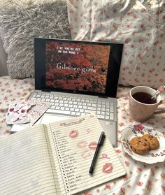 an open laptop computer sitting on top of a bed next to a cup of coffee