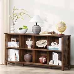 a shelf with books, vases and other items on it next to a lamp