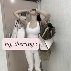 a woman standing in a bathroom with her hand on her head and holding shopping bags