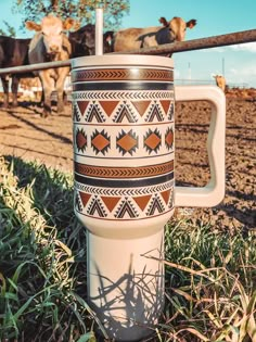 a coffee cup sitting in the grass next to cows