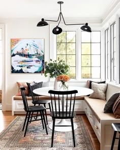 a dining room table with four chairs and a bench in front of the window,