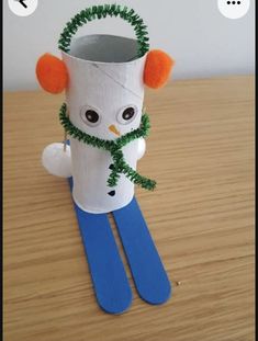 a toilet paper roll snowman sitting on top of a wooden table next to scissors