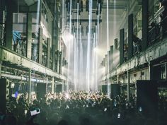 a crowd of people are standing in an alley way with lights coming from the ceiling