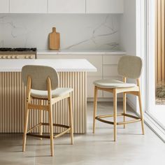 two chairs sitting next to each other in a kitchen near a counter top and cabinets