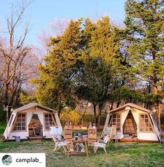 two tents set up in the middle of a field with picnic tables and chairs around them